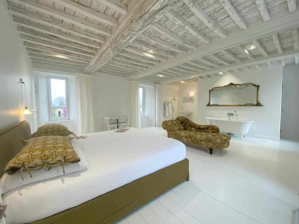 Un dormitorio amplio con una cama grande, un tocador con espejo y una bañera.