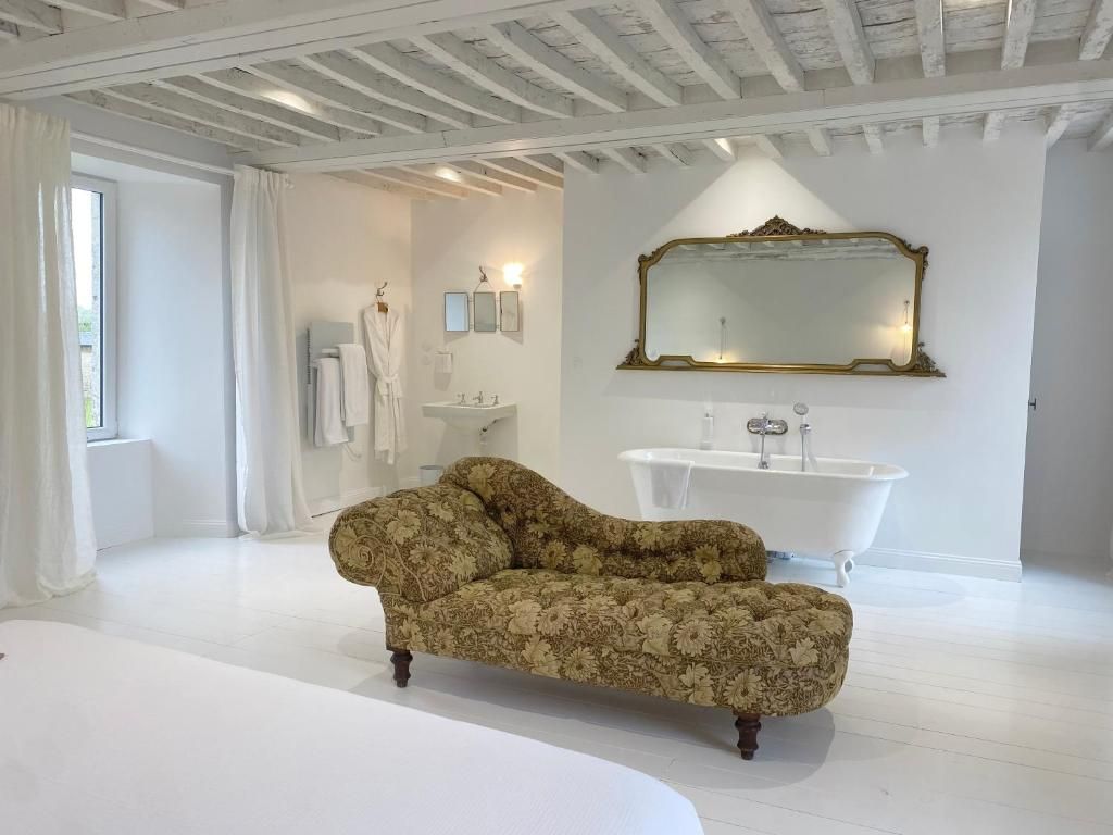 Ein Badezimmer mit einer weißen Badewanne, einem großen Spiegel und einem blumigen Sofa.