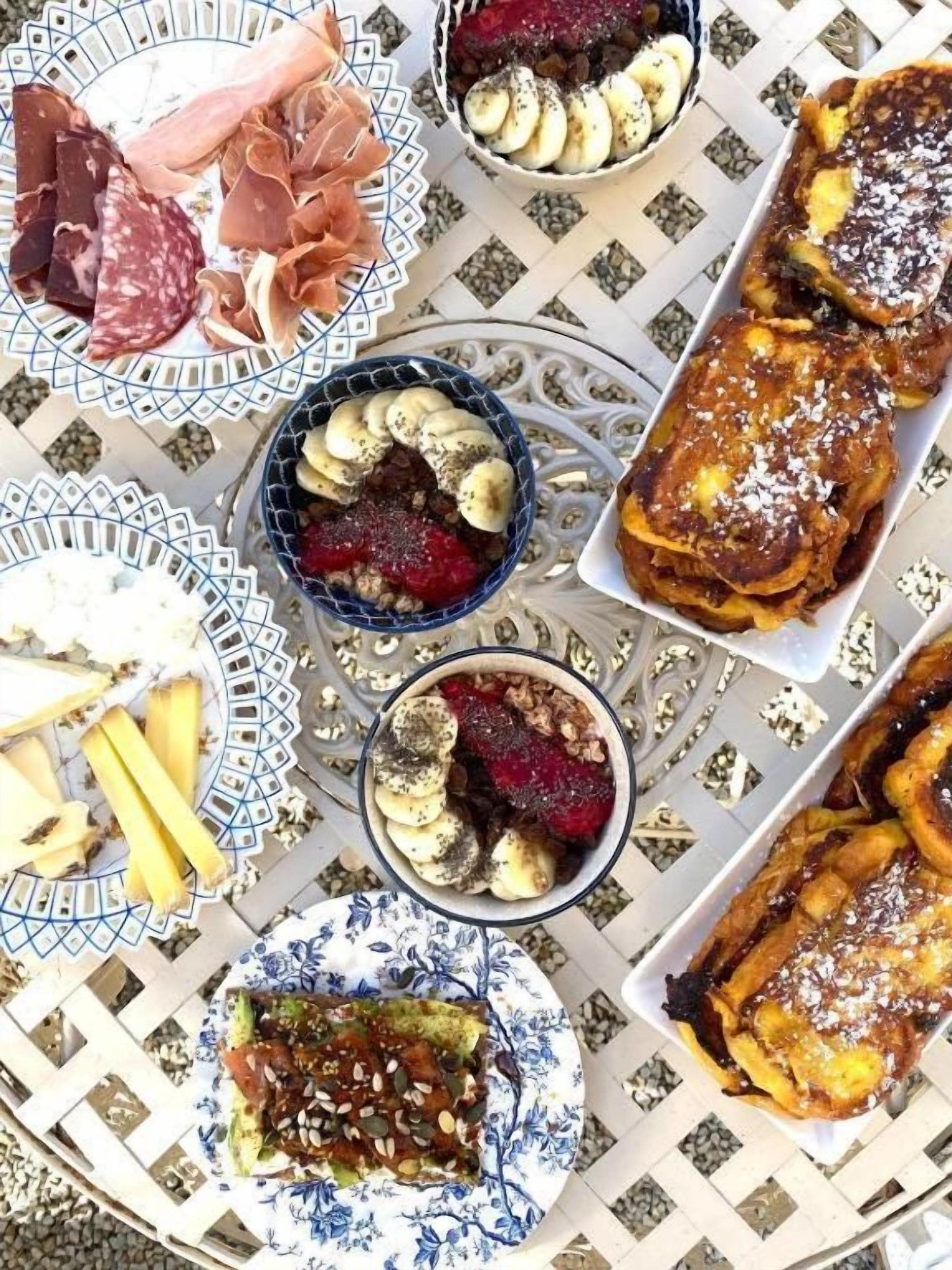Une table où sont présentés divers aliments, notamment des pâtisseries, des fruits et des viandes.