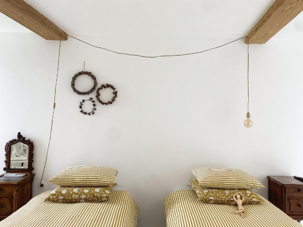 Un dormitorio con dos camas, una lámpara colgante y adornos en la pared.