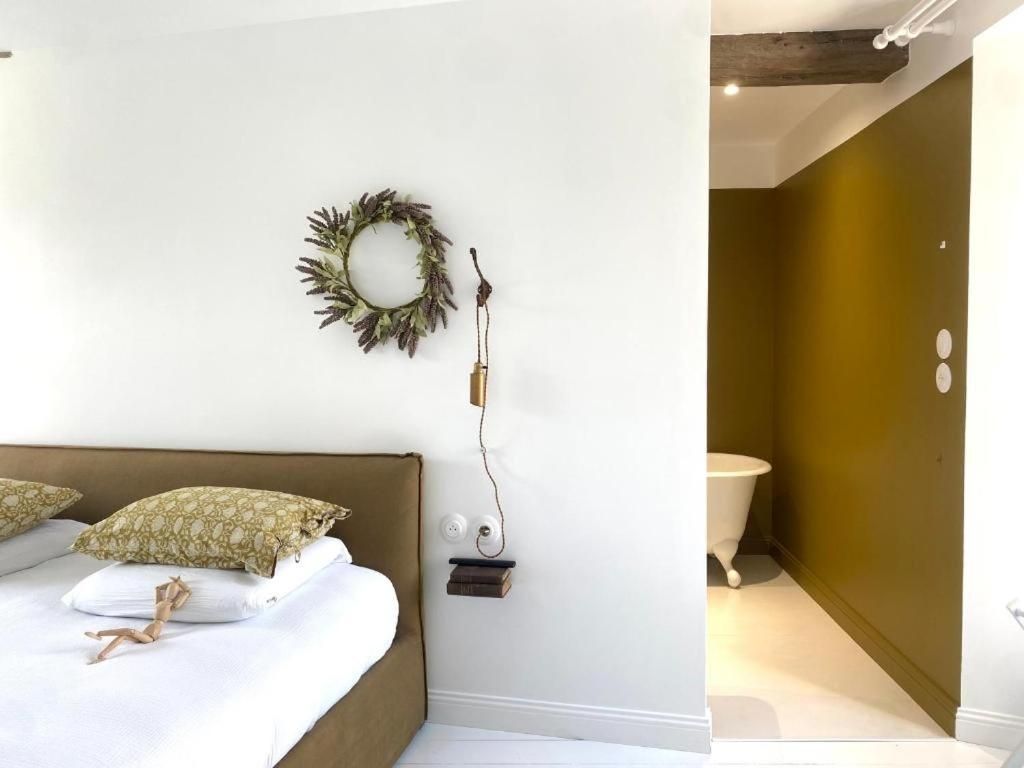 A bedroom with a bed, pillows, a wall-mounted light fixture, and a small shelf.