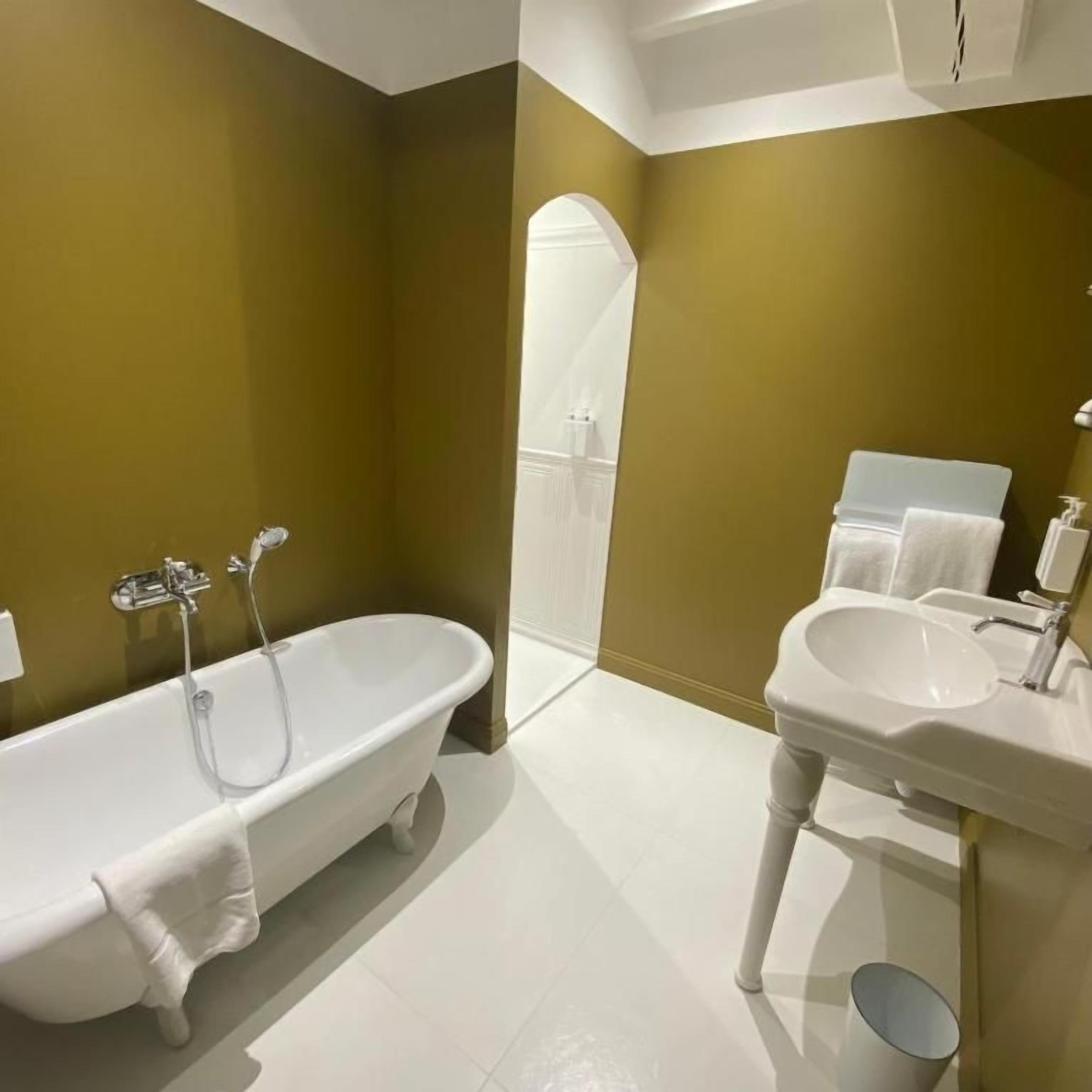A bathroom with a freestanding bathtub, a sink, and a mirror.