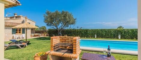 Patio con una parrilla, piscina y mobiliario exterior.