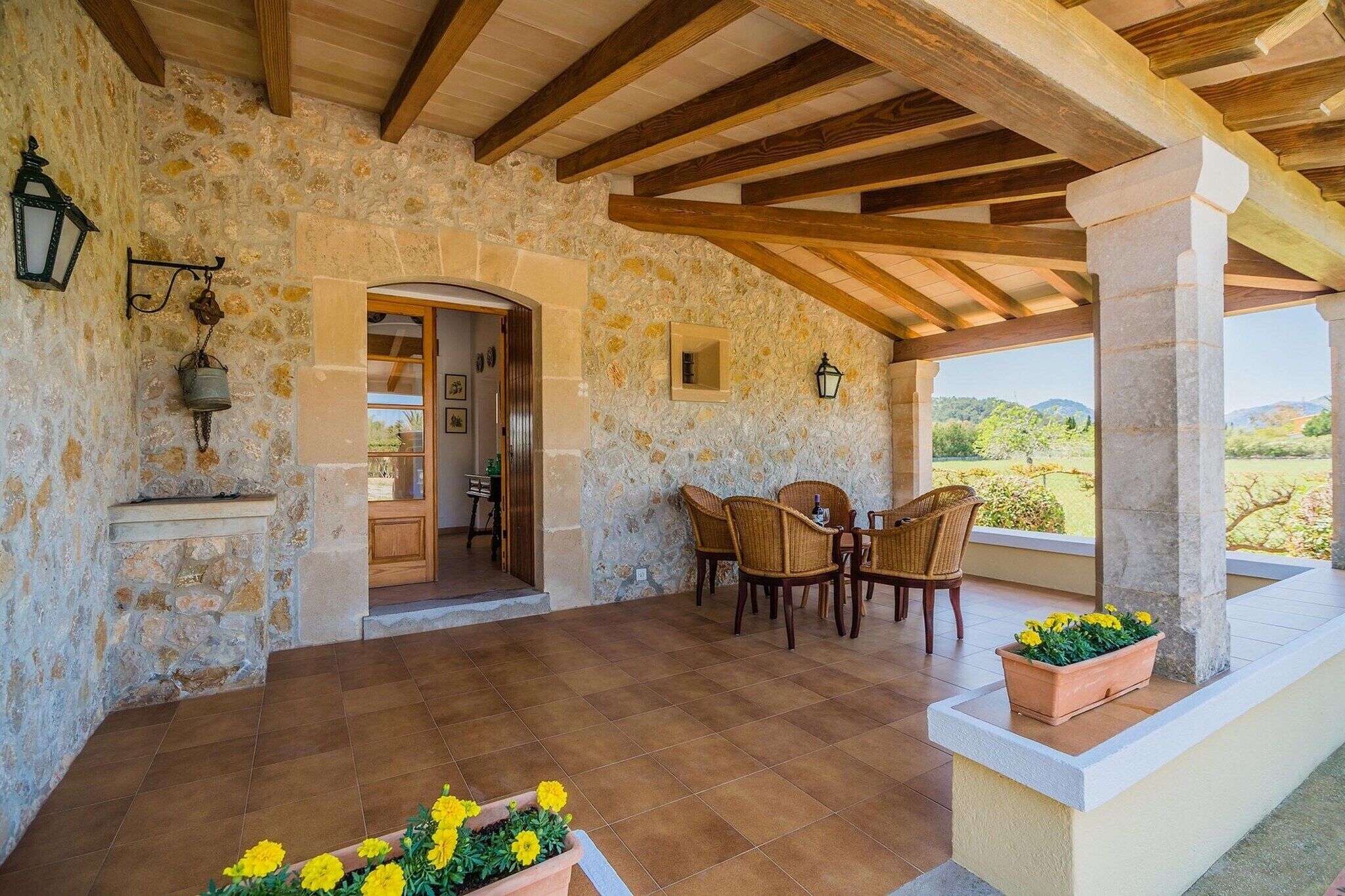 Una habitación con paredes de piedra y techo de madera, una mesa de comedor con sillas y vistas al exterior.