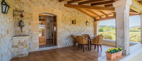 Una habitación con paredes de piedra y techo de madera, una mesa de comedor con sillas y vistas al exterior.