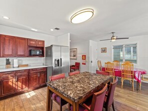 A kitchen with wooden cabinets, a refrigerator, a microwave, and a dining area with a table and chairs. - 5 BR 5 Bath Home Bay side 10 people 2 Car parking (Seaside Heights)