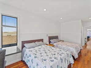 Ein Schlafzimmer mit zwei Betten, einem Fenster und Blick ins Freie.