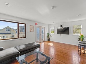 A spacious living room with a black leather sofa, a glass coffee table, and a flat-screen TV mounted on the wall. - 5 BR 5 Bath Home Bay side 10 people 2 Car parking (Seaside Heights)