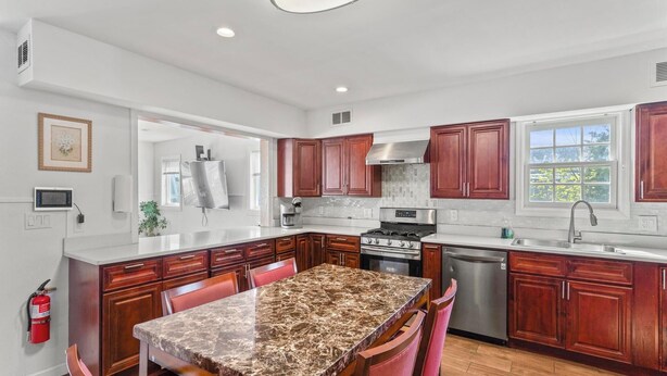 A modern kitchen with a central island, stainless steel appliances, and wooden cabinetry. - 5 BR 5 Bath Home Bay side 10 people 2 Car parking (Seaside Heights)