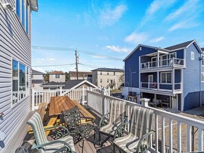 Eine Terrasse mit Gartenmöbeln, Blick auf benachbarte Häuser und einen klaren Himmel.