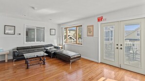 A spacious living room with a large sectional sofa, a glass coffee table, and hardwood flooring. - 5 BR 5 Bath Home Bay side 10 people 2 Car parking (Seaside Heights)