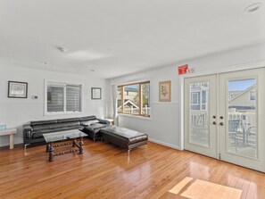 A spacious living room with a large sectional sofa, a glass coffee table, and hardwood flooring. - 5 BR 5 Bath Home Bay side 10 people 2 Car parking (Seaside Heights)