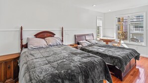 A bedroom with two beds, wooden headboards, a bedside table with a lamp, and a window with blinds. - 5 BR 5 Bath Home Bay side 10 people 2 Car parking (Seaside Heights)