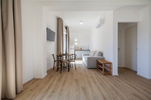 Un espacio moderno de estar con comedor, sofá y una pequeña mesa.