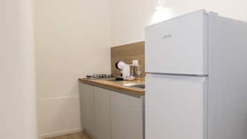 Une cuisine de taille réduite, avec un réfrigérateur blanc, une cuisinière à gaz et un plan de travail en bois.