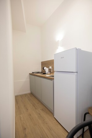 A compact kitchen with a white refrigerator, a gas stove, and a wooden countertop.