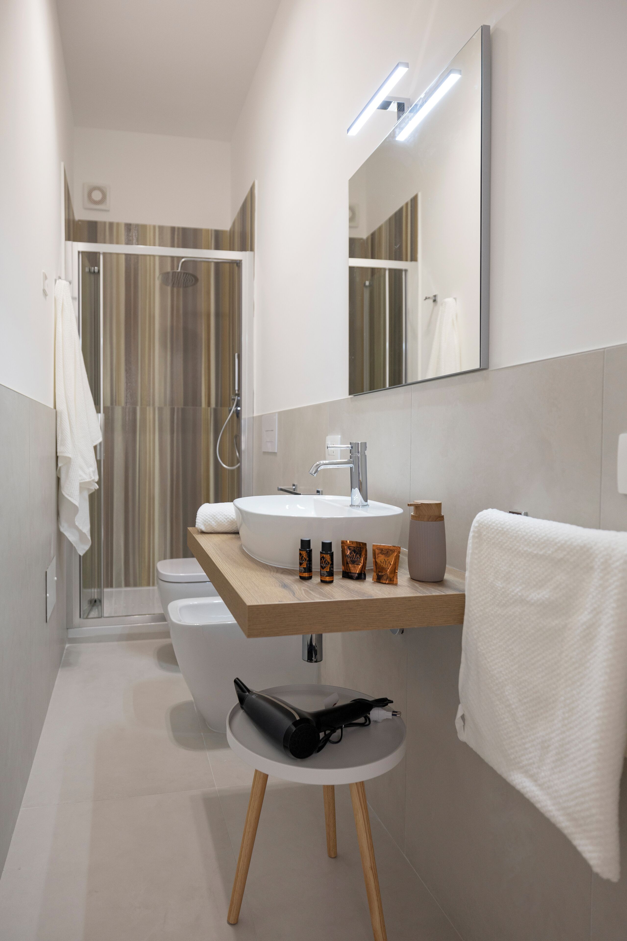 Un baño moderno con lavamanos, espejo y toallero blancos.