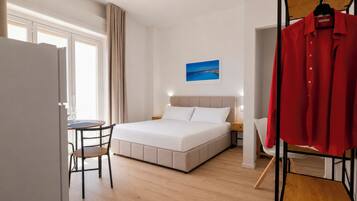 Een hotelkamer met een bed, een bureau, een stoel, een kledingkast en een schilderij aan de muur.