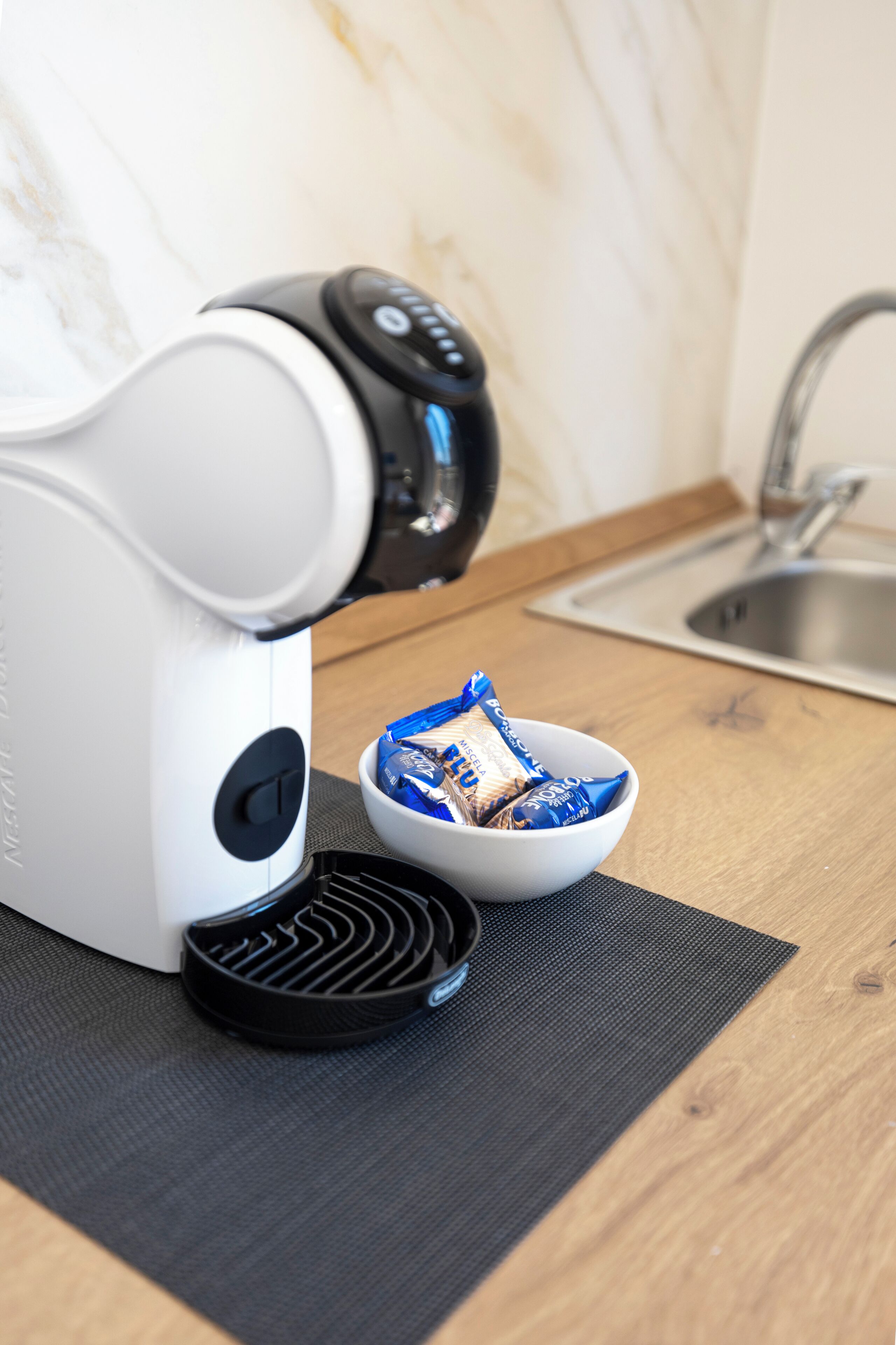 Eine Küche mit einer Kaffeemaschine, einer Schale mit Snacks und einem Spülbecken.