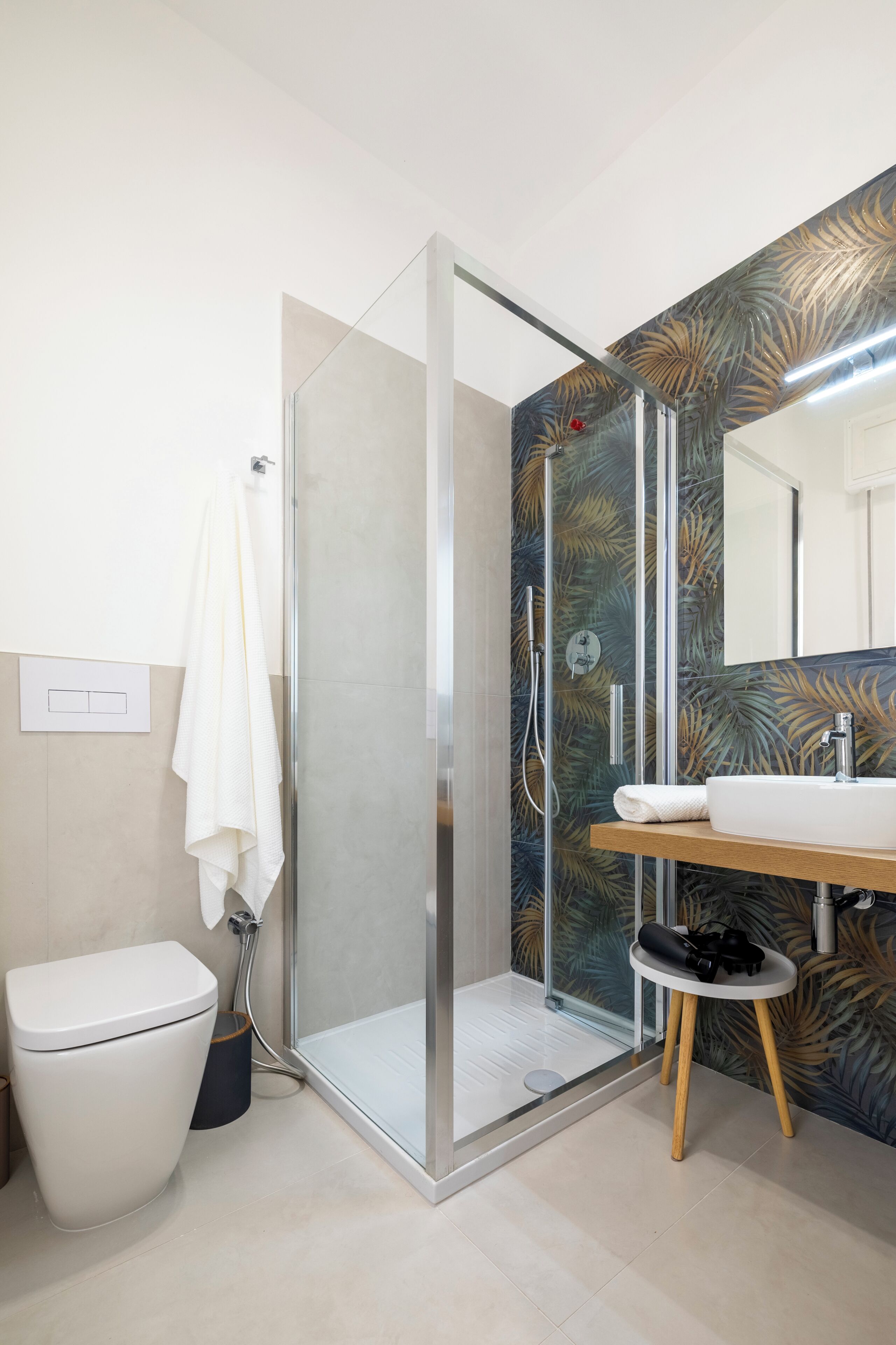 A modern bathroom with a glass-enclosed shower, a toilet, and a sink with a wooden countertop.