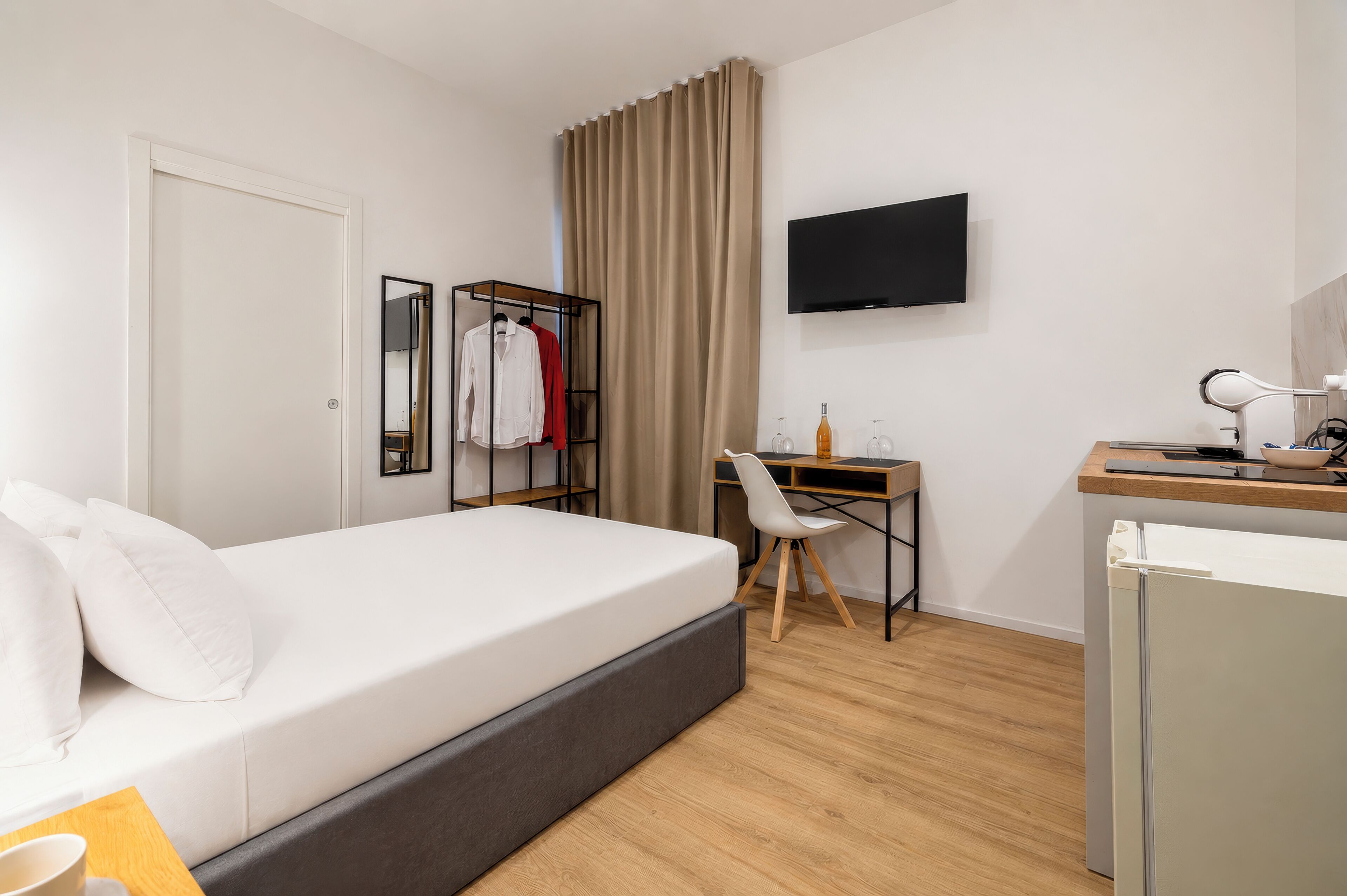 Habitación de hotel con cama, escritorio, silla, televisor y armario.