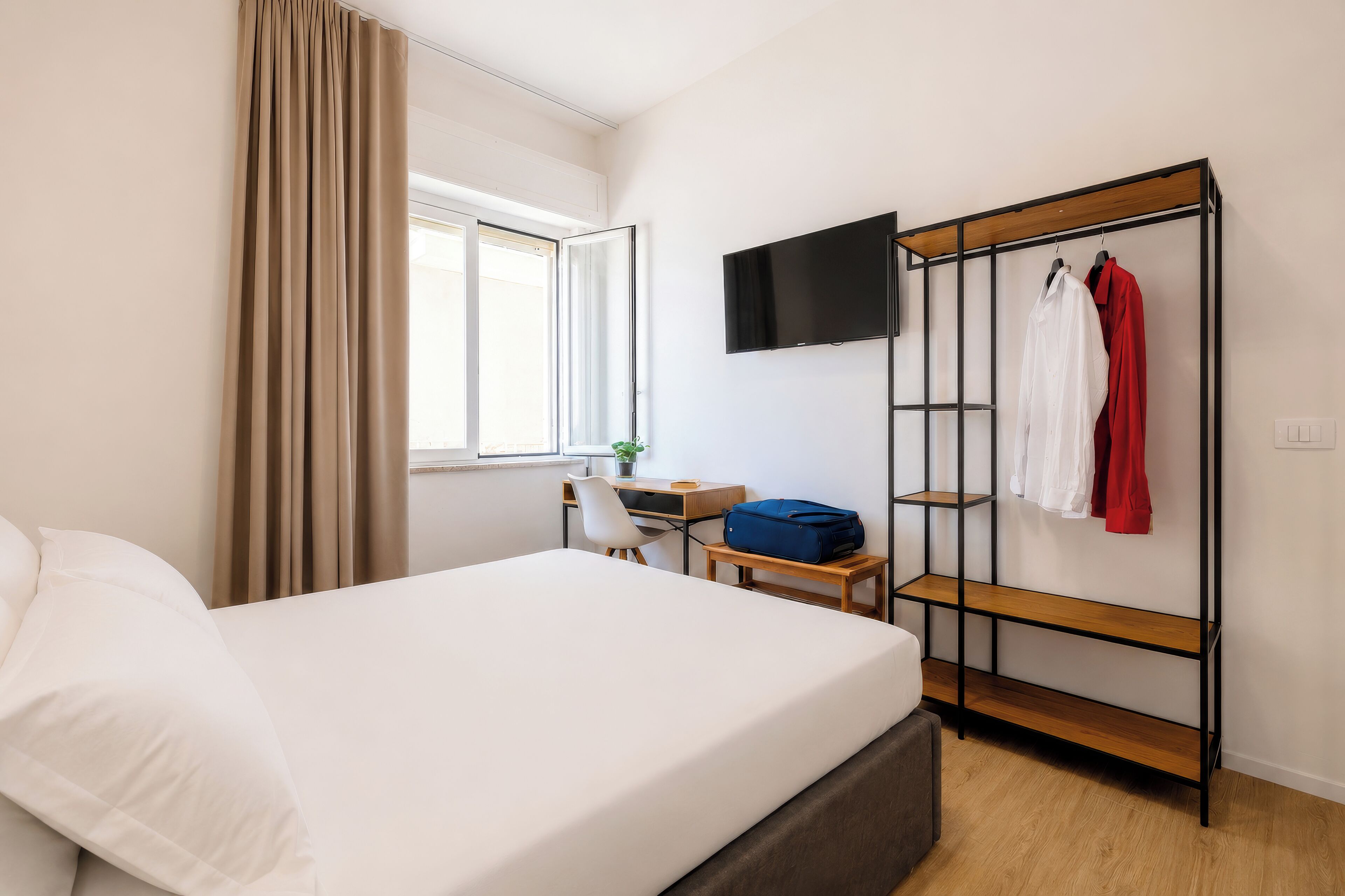 Ein Hotelzimmer mit Bett, Schreibtisch, Fernseher und Kleiderschrank.