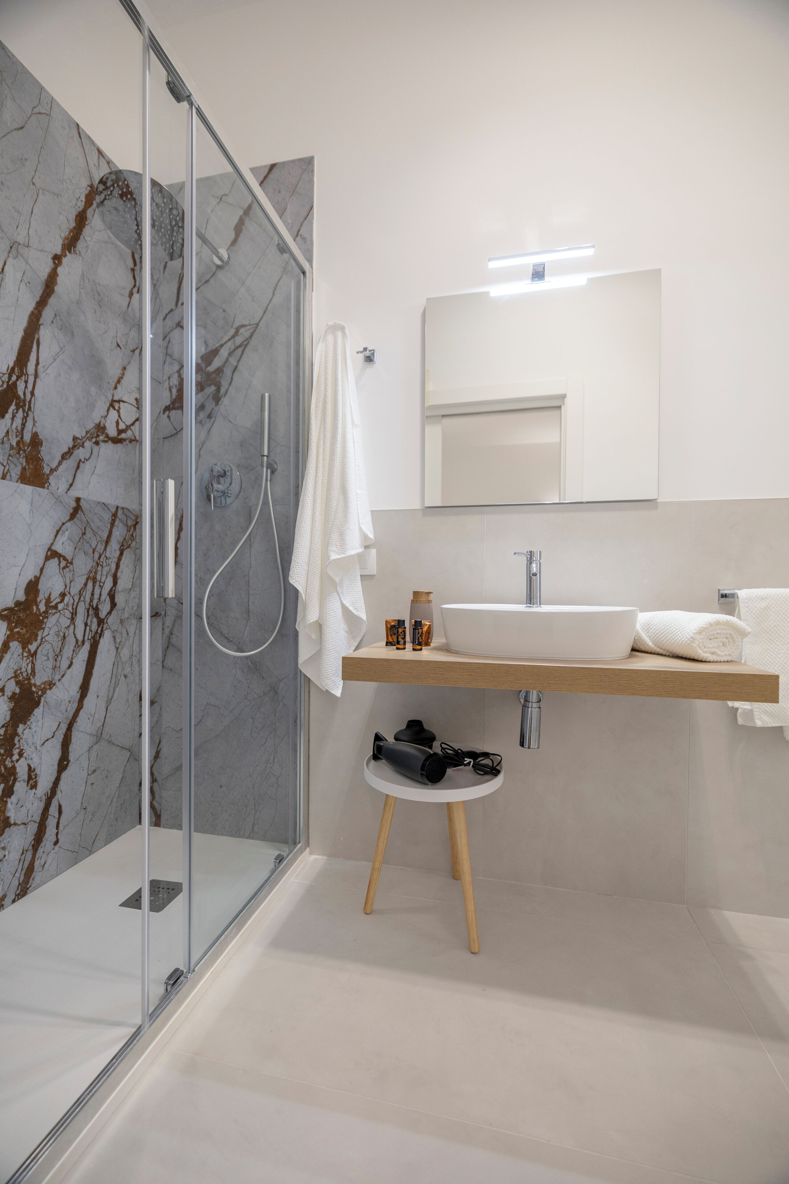 A modern bathroom with a glass-enclosed shower, a white sink, and a mirror above it.