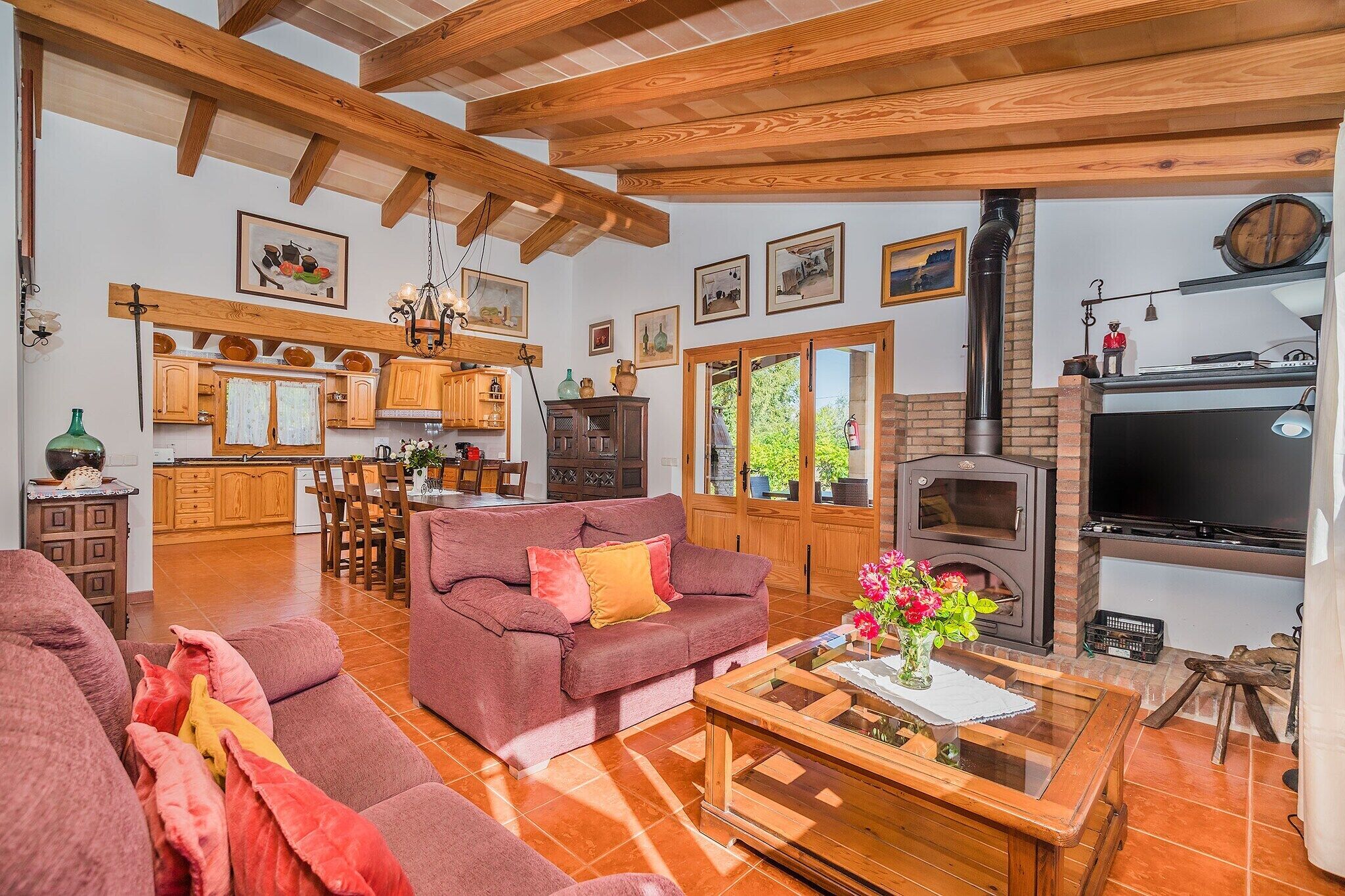 A cozy living room with a fireplace, a dining area, and a kitchen with wooden beams.