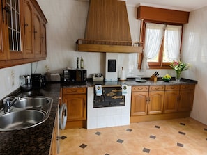 Una cocina con armarios de madera, un lavamanos de acero inoxidable, un microondas y un refrigerador.