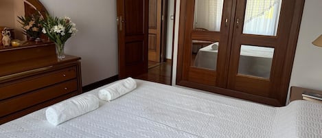 Habitación de hotel con cama, cómoda, espejo y puerta que da a otra habitación.