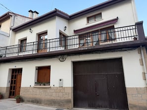 Un edificio de dos pisos con balcón, garaje y base de piedra.