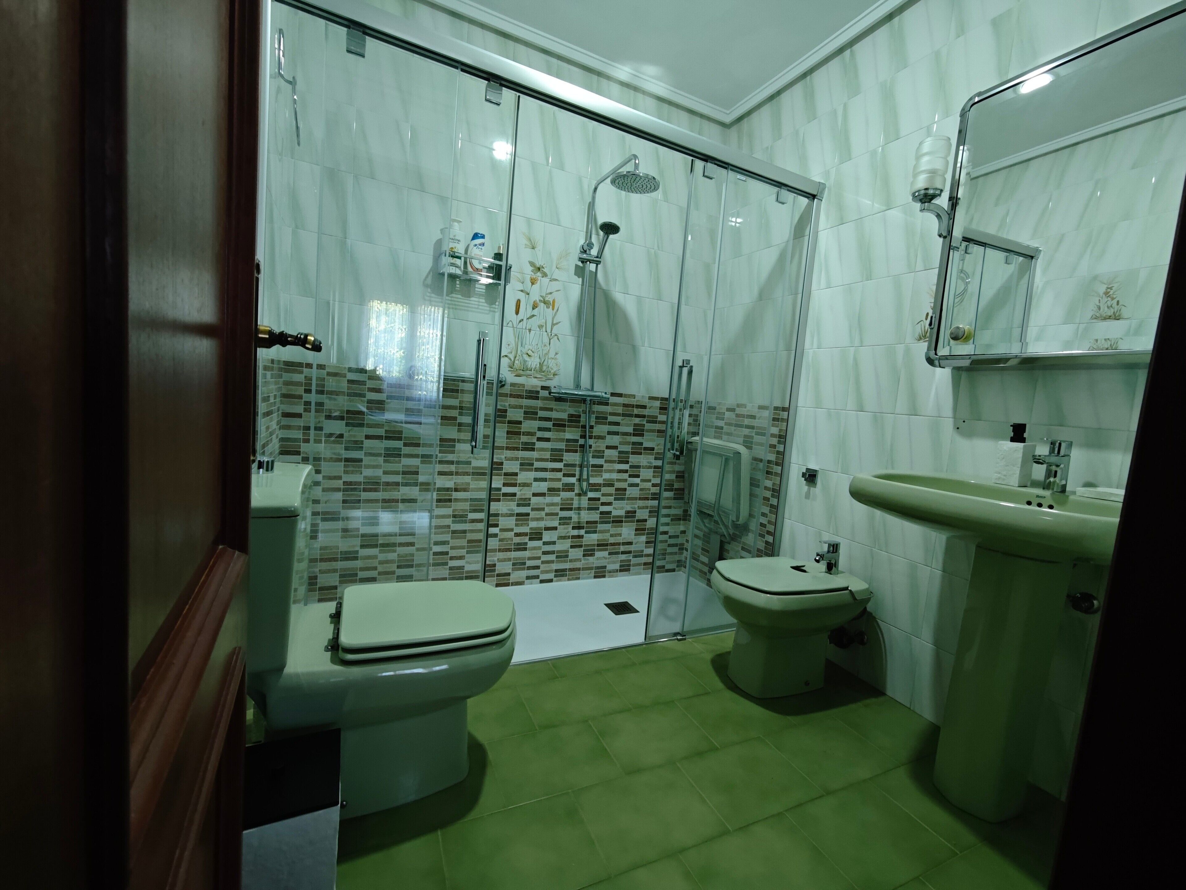 Une salle de bain avec une douche à parois de verre, des toilettes et un lavabo.