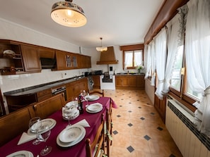 A kitchen with wooden cabinets, a dining table set for four, and a window with curtains. - Holiday Home 'Podium' with Mountain Views, Large Terraces and Wi-Fi (Villabuena de Álava / Eskuernaga)