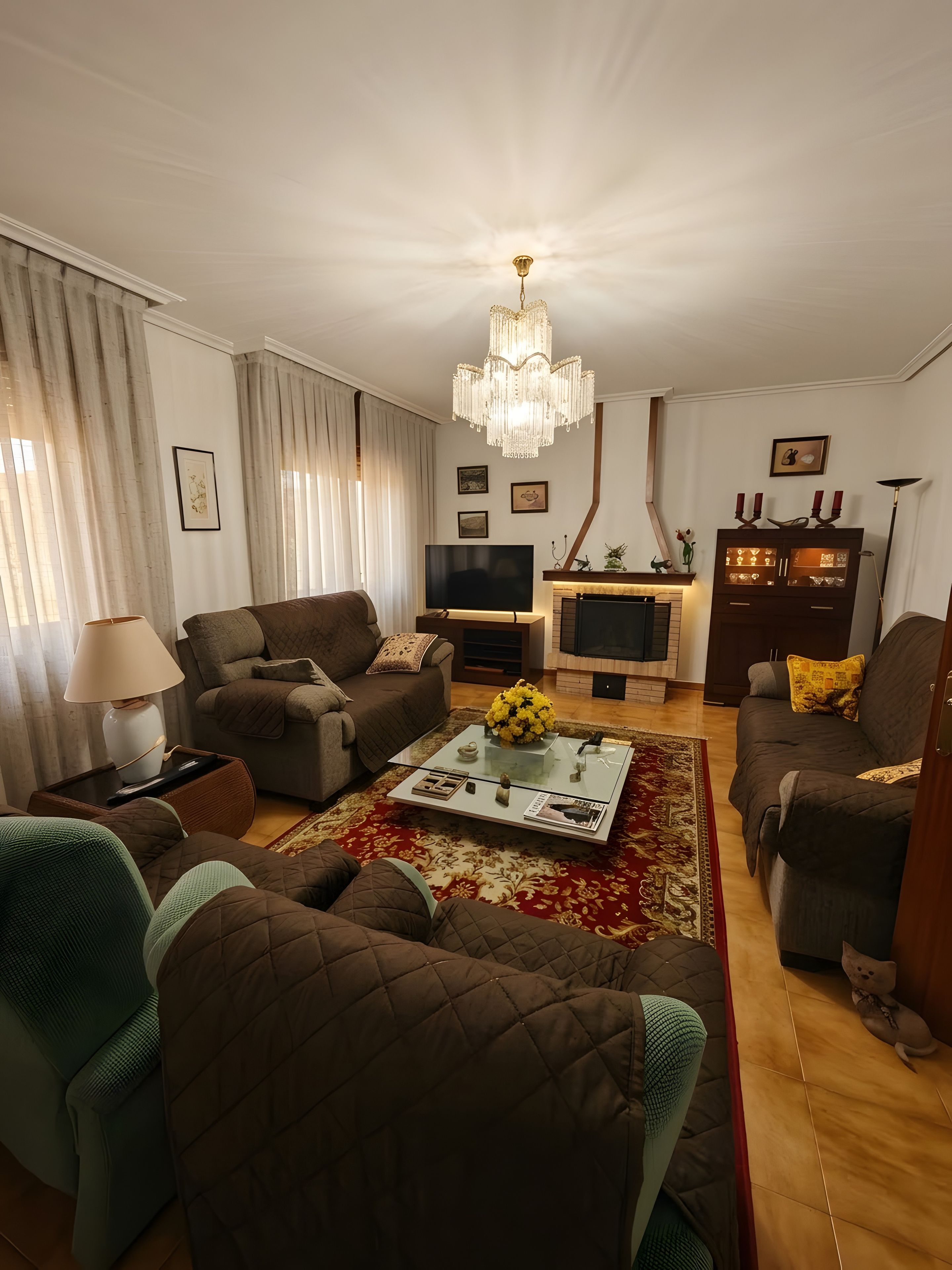 Een moderne woonkamer met een open haard, een televisie en een kroonluchter.