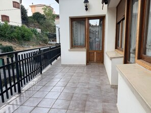 A balcony with a tiled floor, a black metal railing, and a wooden door with a window. - Podium Holiday Home with Mountain Views, Balcony, and Wi-Fi (Villabuena de Álava / Eskuernaga)