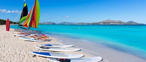 A beach with surfboards and a sailboat.