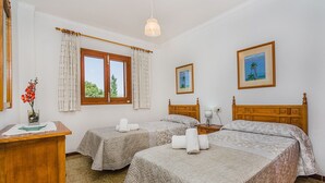 Une chambre d’hôtel avec deux lits, un bureau, une lampe et un tableau au mur.