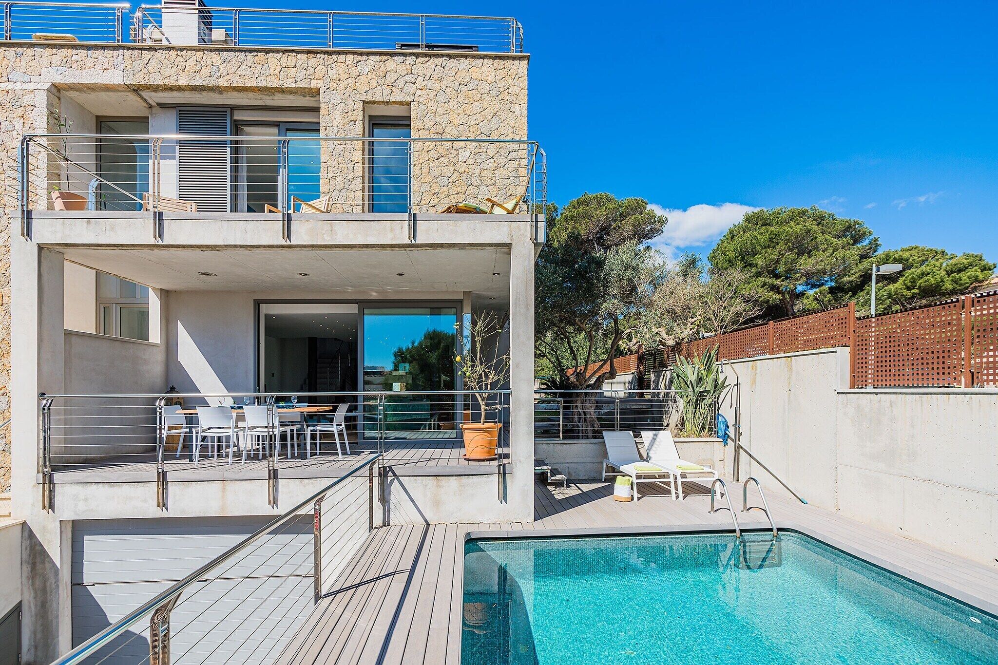Ein modernes Gebäude mit Pool, Außenbereich zum Sitzen und einer Treppe zu einem überdachten Bereich.
