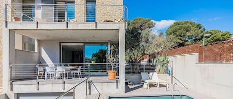 Ein modernes Gebäude mit Pool, Außenbereich zum Sitzen und einer Treppe zu einem überdachten Bereich.