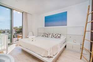 Ein modernes Schlafzimmer mit einem großen Bett, Meerblick durch das Fenster und einem Gemälde an der Wand.