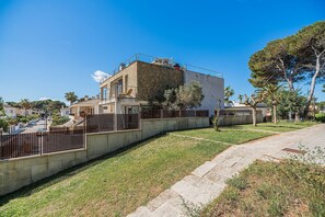 Ein Wohngebäude mit Steinverkleidung, einem Balkon und einem umzäunten Garten.