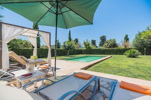 A poolside area with lounge chairs, a table with drinks, and a pergola with a green canopy. - Private Pool Villa in Pollensa (Pollensa / Pollença)
