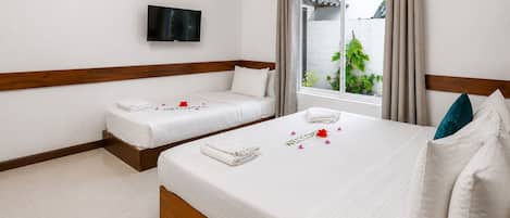 A hotel room with two beds, a flat-screen TV, a window with curtains, and a potted plant.