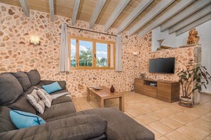 Ein Wohnzimmer mit Steinwänden, einer Couch, einem Fernseher und einem Fenster mit Blick.