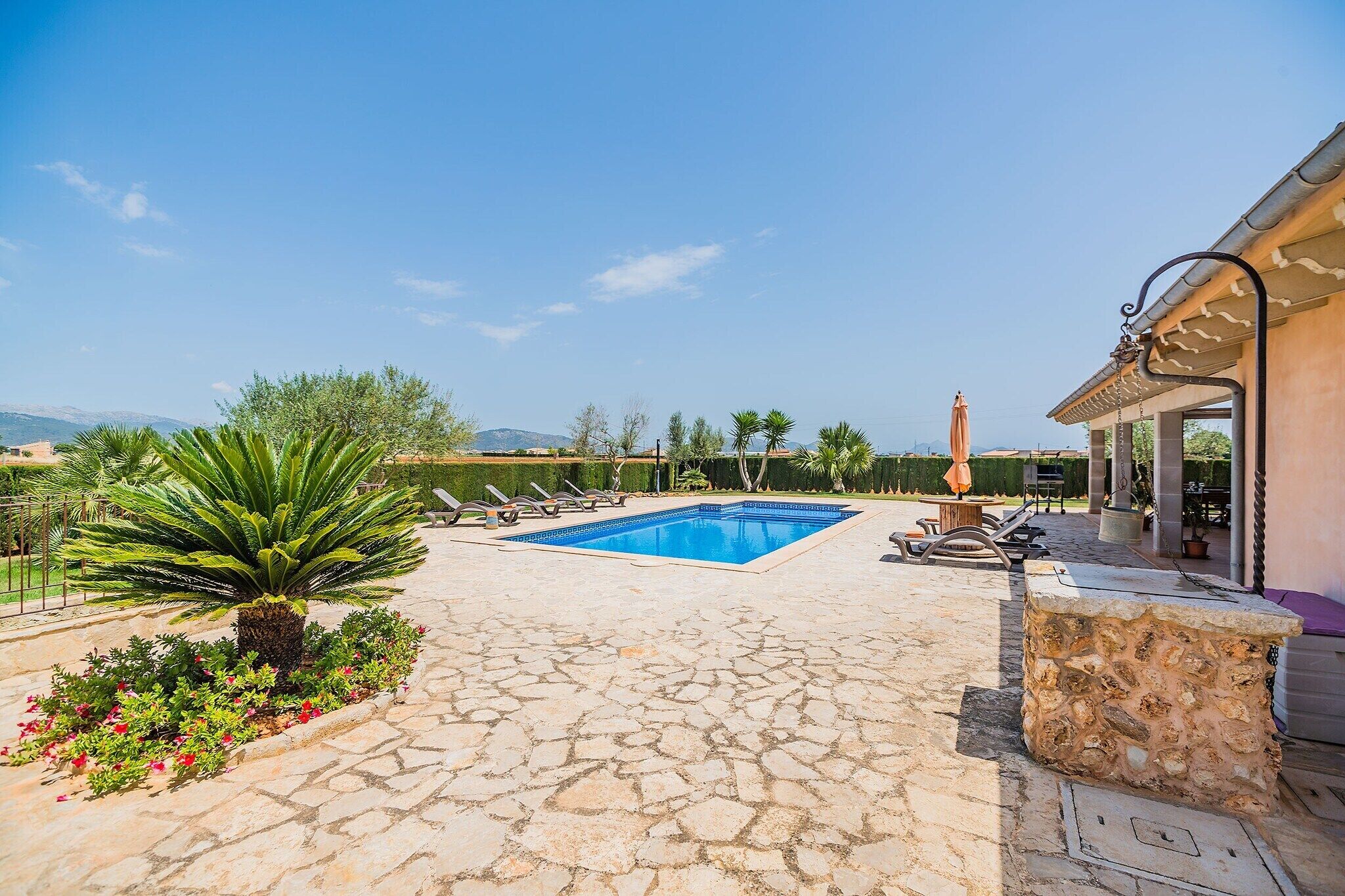 A swimming pool with a stone patio, lounge chairs, and a view of the mountains.