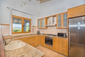 Una cocina con encimeras de granito, electrodomésticos de acero inoxidable, armarios de madera y un ventanal con vistas.