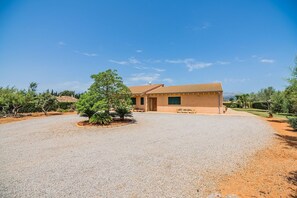 A single-story building with a gravel driveway, surrounded by landscaped gardens and trees. - Peaceful Country Villa in Sa Pobla (Sa Pobla)