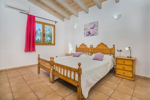A bedroom with a wooden bed, a nightstand, a dresser, a window with a curtain, and a wall-mounted light fixture. - Peaceful Country Villa in Sa Pobla (Sa Pobla)