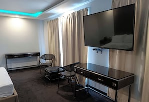 A hotel room with a bed, a desk, a chair, a TV, and curtains. - The Fields Palace Hotel Premier (Angeles City)