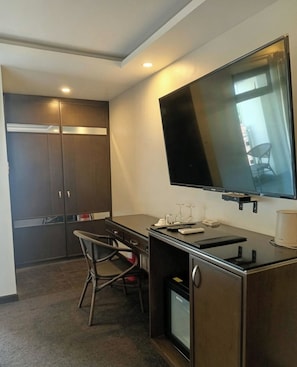 Una habitación de hotel pequeña con escritorio, silla, televisión y armario.